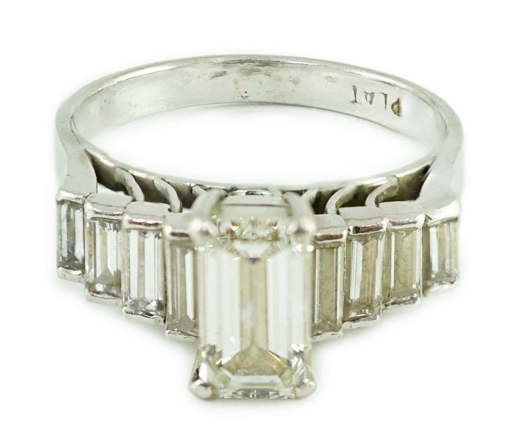 A modern platinum and emerald cut single stone diamond ring, with stepped graduated baguette cut diamond set shoulders